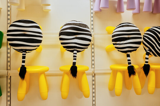 Bright yellow children stools with zebra-patterned cushions displayed in store. Concept represents creativity, playfulness, and modern design