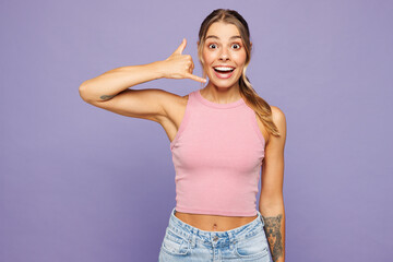 Young shocked surprised happy woman she wear pink tank top casual clothes doing phone gesture like says call me back isolated on plain pastel light purple background studio portrait Lifestyle concept