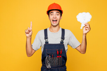 Young employee laborer handyman man wears helmet overall say cloud with lightbulb point finger up...