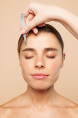 Close up half naked topless young woman 20s with nude make up pluck out hair with tweezers isolated...