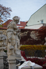 Historic stone statue in autumn garden with ivy-covered wall