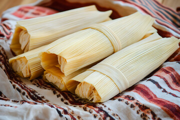 Authentic chicken tamales, still wrapped in their corn husks, ready for serving on a vibrant patterned cloth