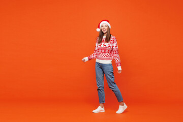 Full body side view merry smiling young woman wear red knitted Christmas sweater Santa hat posing...