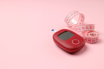 Blood glucose meter and tape on pink background