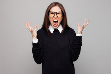 Young angry mad successful employee business woman corporate lawyer she wear black sweater shirt work in office spread hands look camera scream isolated on plain grey color background studio portrait.