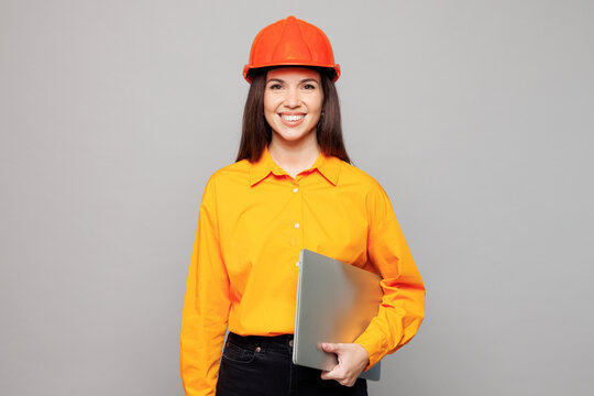 Young architect engineer designer employee white IT woman she wear yellow clothes hardhat hold closed laptop pc computer isolated on plain grey background studio portrait People work on build project.