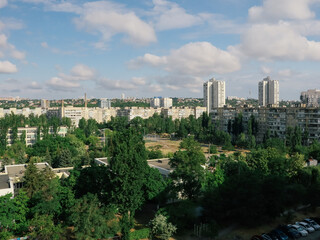 Cityscape view of residential buildings and green trees under a blue sky. This aerial view showcases a city with apartment buildings and lush green trees on a sunny day