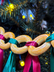 Colorful garland made of ring-shaped cookies and ribbons hangs on a decorated tree