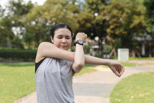 women stretching arms before workout in outdoor park, showing warm-up exercise and healthy lifestyle. Concept of fitness preparation, flexibility and physical wellness.