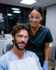 Fototapeta premium A dental professional smiling with a patient seated in the dental chair while preparing for a dental consultation, showcasing a friendly and caring environment.