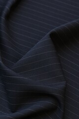 Closeup of luxurious, dark navy cool wool suiting fabric with a subtle, elegant pin stripe pattern,...