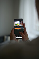 Closeup of a woman using a smartphone app to watch a delivery man dropping off a package