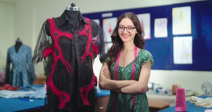 Indian young adult gen z lady female wear tape around neck cross arms look camera standing near table at class room teen pupil girl fold hand staring cam do pose learn new craft cloth course day place