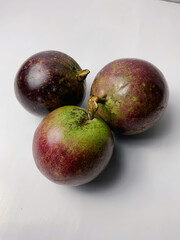 Three ripe star apples, also known as cainito or caimito, are displayed on a white background, showcasing their unique purple and green skin