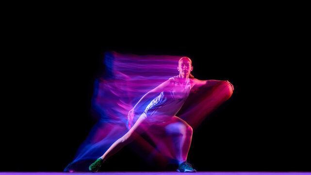 Focused basketball player in defensive stance with neon motion blur. Concept of teamwork strategy, game preparation, performance coaching, and sports marketing for fitness brands.