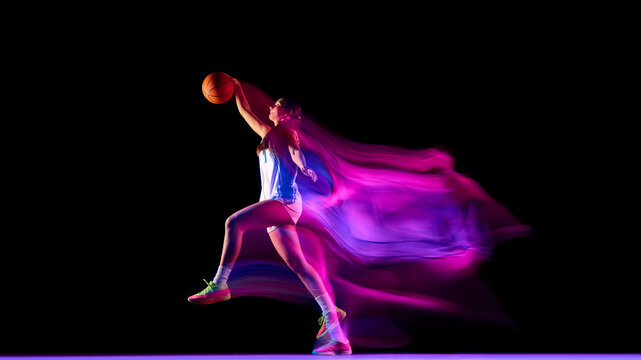 Basketball player in jump shot pose surrounded by neon light trails. Concept of sports advertising, fitness branding, modern energy campaigns, and motivational design visuals.