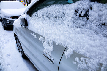 Snow covers parked cars on a winter day in a city street creating a serene, chilly atmosphere that highlights the beauty of the season