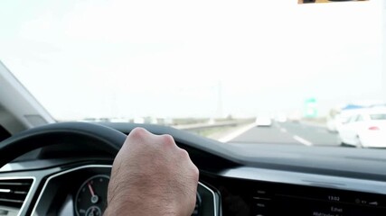 Driving car on highway. Hands on steering wheel inside of a car. view from car interior while driving a car on highway. Drivers hand holding steering wheel and driving on highway during day.