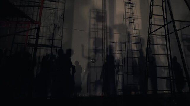 Footage of shadows of dancers and stage crew projected on a backstage wall under dramatic
lighting creating artistic silhouettes and geometric ladder patterns in theater performance settings.