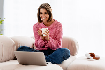 Young woman relaxing at home using laptop