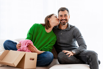 Young couple unpacking box and kissing in new home