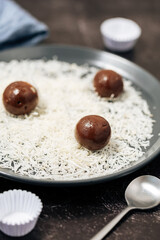 Close-up of traditional Brazilian brigadeiro being coated in grated coconut on a plate, highlighting the homemade preparation of this popular sweet served at birthday parties