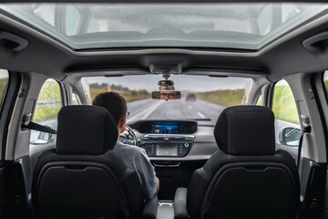 Driver on rainy road trip. Autumn day behind the wheel.