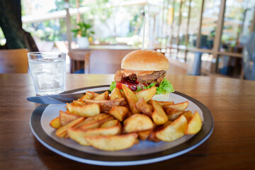 A woman is sitting at a restaurant table enjoying a delicious fried chicken burger with potato...