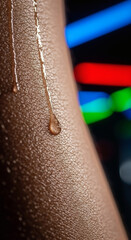 Extreme macro close-up of a sweat drop rolling down human skin with blurred neon lights in the background, symbolizing high-intensity workout, heat, and physical endurance.