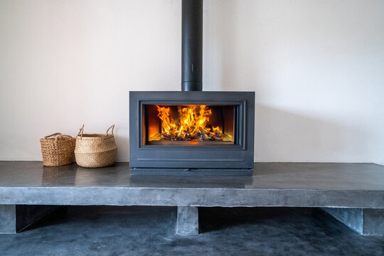 Fireplace inside house modern living room. Cosy living room with wood burner stove with burning flame behind a glass door	