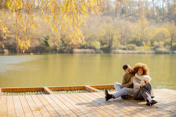 Couple enjoying a peaceful day by the serene lake during autumn's golden embrace