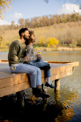 Fototapeta premium Couple enjoys a peaceful lakeside moment on a sunny autumn afternoon