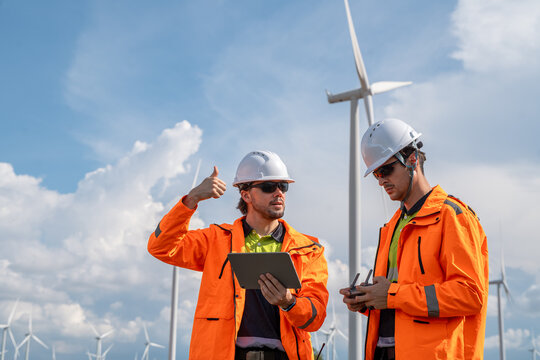 Engineers using drone and tablet for wind turbine inspection at wind farm. Two engineers (two men) operating a drone for inspecting wind turbines, concept of technology and sustainability. - Powered by Adobe