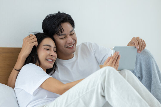 Happy couple watching movies and dramas on the bed - Powered by Adobe