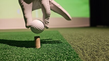 Golf ball getting ready to be struck from a tee at an indoor simulation facility concept