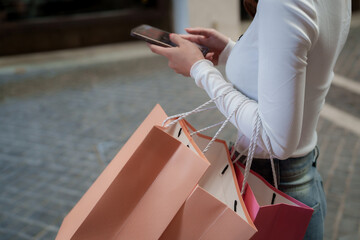 A person holds multiple shopping bags in both hands while walking outdoors, suggesting a successful...