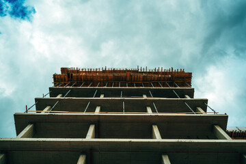 Fototapeta premium Low angle view of modern corporate office building construction site, concrete frame structure with scaffolding