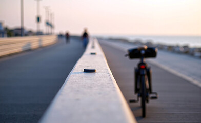 Bicycle parked near a seaside promenade at sunset, soft light and shallow depth of field creating calm travel atmosphere.