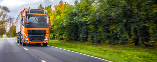 Orange truck driving on road. Power and innovation in motion.