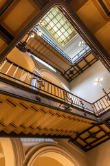 Light and symmetry in a historic atrium. Upward view through stairs.