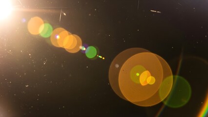 Bright sunlight lens flare effect with orange and green hues against a dark background
