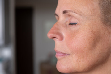 Close up of mature woman face with natural skin texture. Concept of aging, skincare, health, wellness, and real beauty showing realistic skin and wrinkles detail.