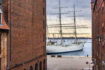 Tall ship between brick warehouses. Maritime classic.