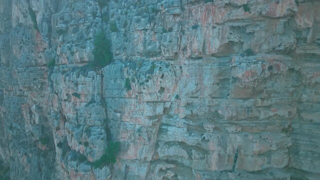 Drone footage of rocky cliffs at Cala del Moraig in Benitatxell, Spain. Detailed close-up of Mediterranean rock textures and natural stone formations.
