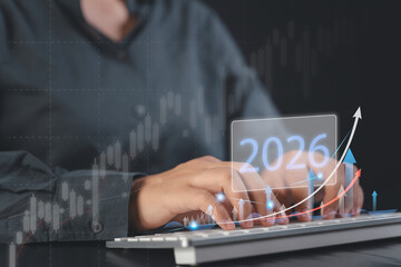 Hands typing with 2026 hologram rising arrows and candlestick charts indicating digital business growth forecasting and market analytics