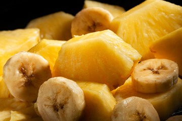 sliced pineapple banana mix on black background