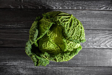 savoy cabbage on black wood background top view