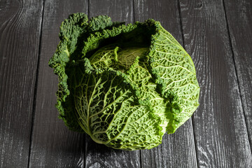 savoy cabbage on black wood background