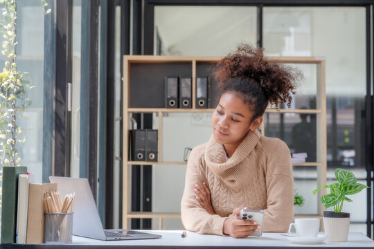 A happy professional businesswoman worker employee sitting at a desk working on a laptop in a corporate setting. A smiling female student using computer technology learning online, doing web research.