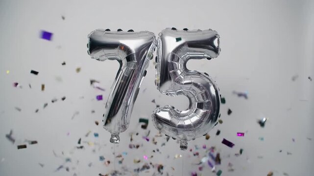Silver balloon number 75 for birthday or anniversary party. White background with falling confetti